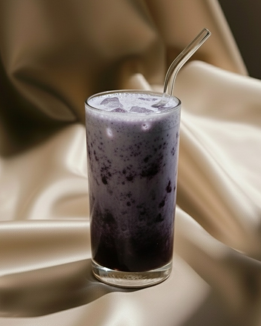 Blueberry vanilla collagen shake in a tall glass, deep violet at the base fading to pale lavender, with a glass straw